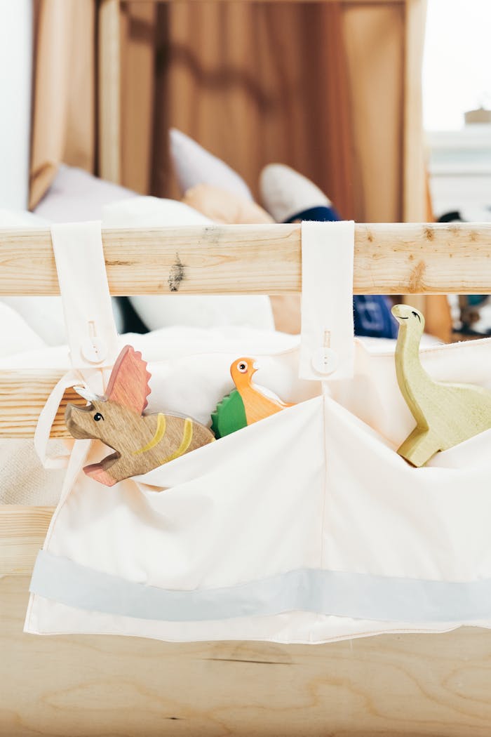 A cozy playroom showcasing wooden dinosaur toys in a fabric pouch on a wooden bed.